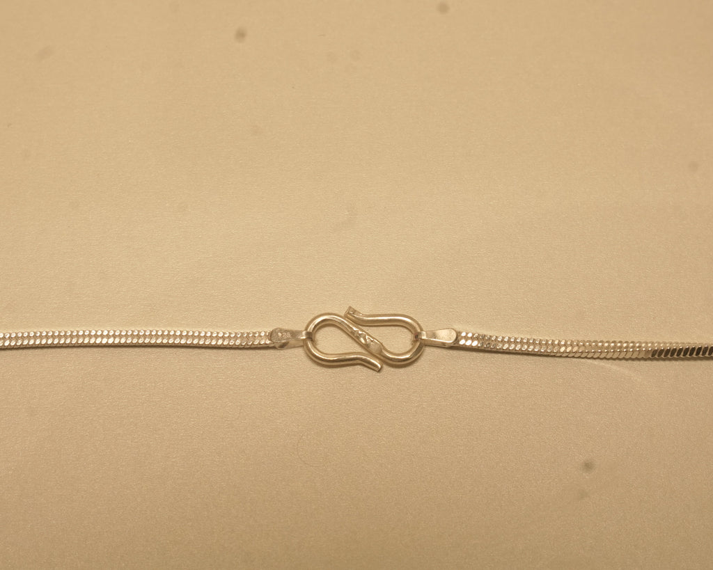 Close view of the S hook clasp joining the two ends of the silver flat snake chain.