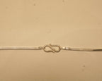Close view of the S hook clasp joining the two ends of the silver flat snake chain.