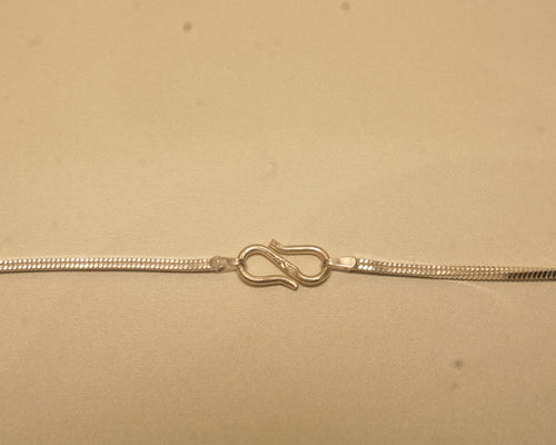 Close view of the S hook clasp joining the two ends of the silver flat snake chain.