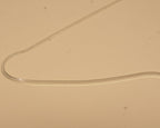 Close view of the silver flat snake chain curving across a pale surface.