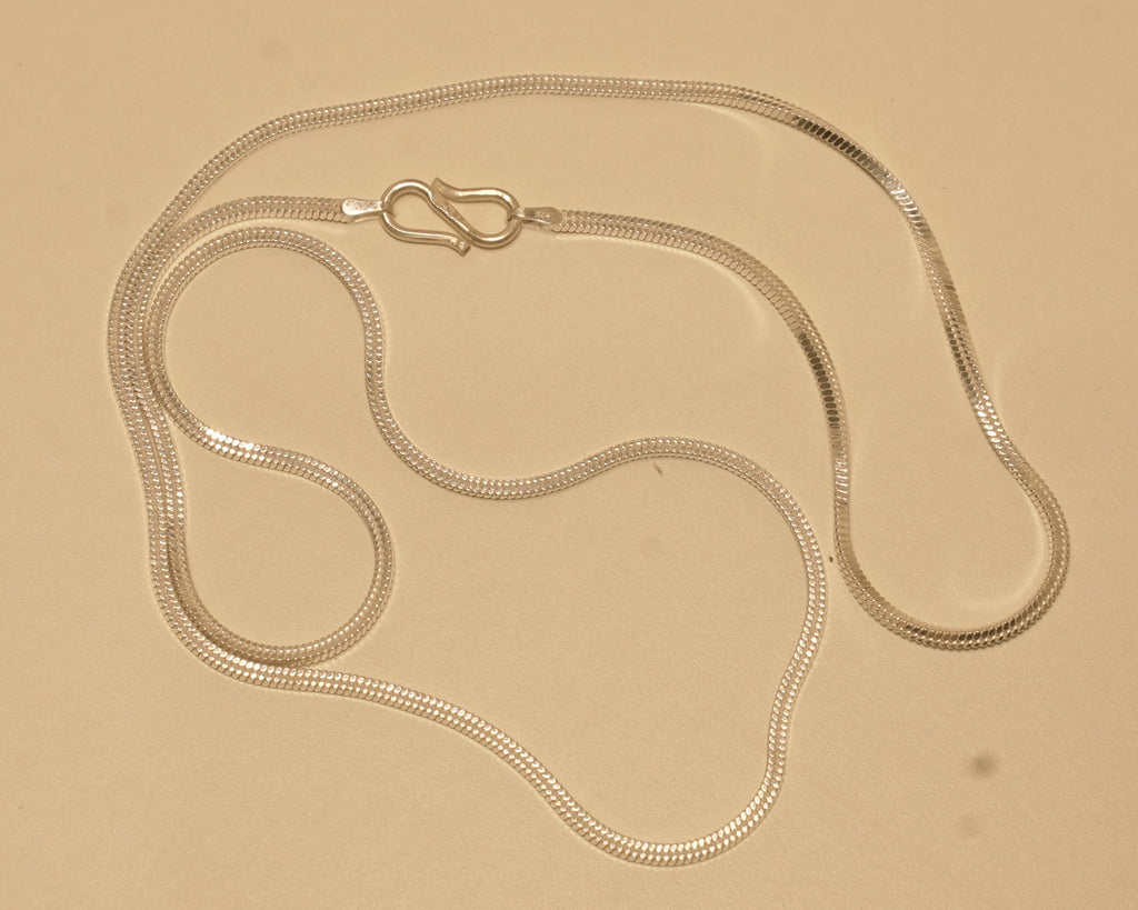 The silver flat snake chain coiled loosely with the S hook near the top.