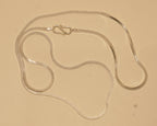 The silver flat snake chain coiled loosely with the S hook near the top.