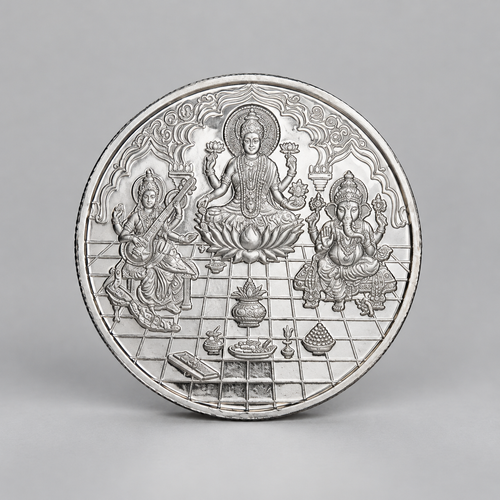 10 gram fine silver coin with Lakshmi on a lotus between Ganesh and Saraswati, on a grey surface.
