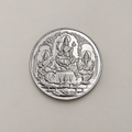20 gram fine silver coin with Lakshmi, Ganesh and Saraswati under temple arches, on a beige surface.