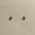 Pair of small round cubic zirconia solitaire stud earrings in prong-set sterling silver on handmade paper.