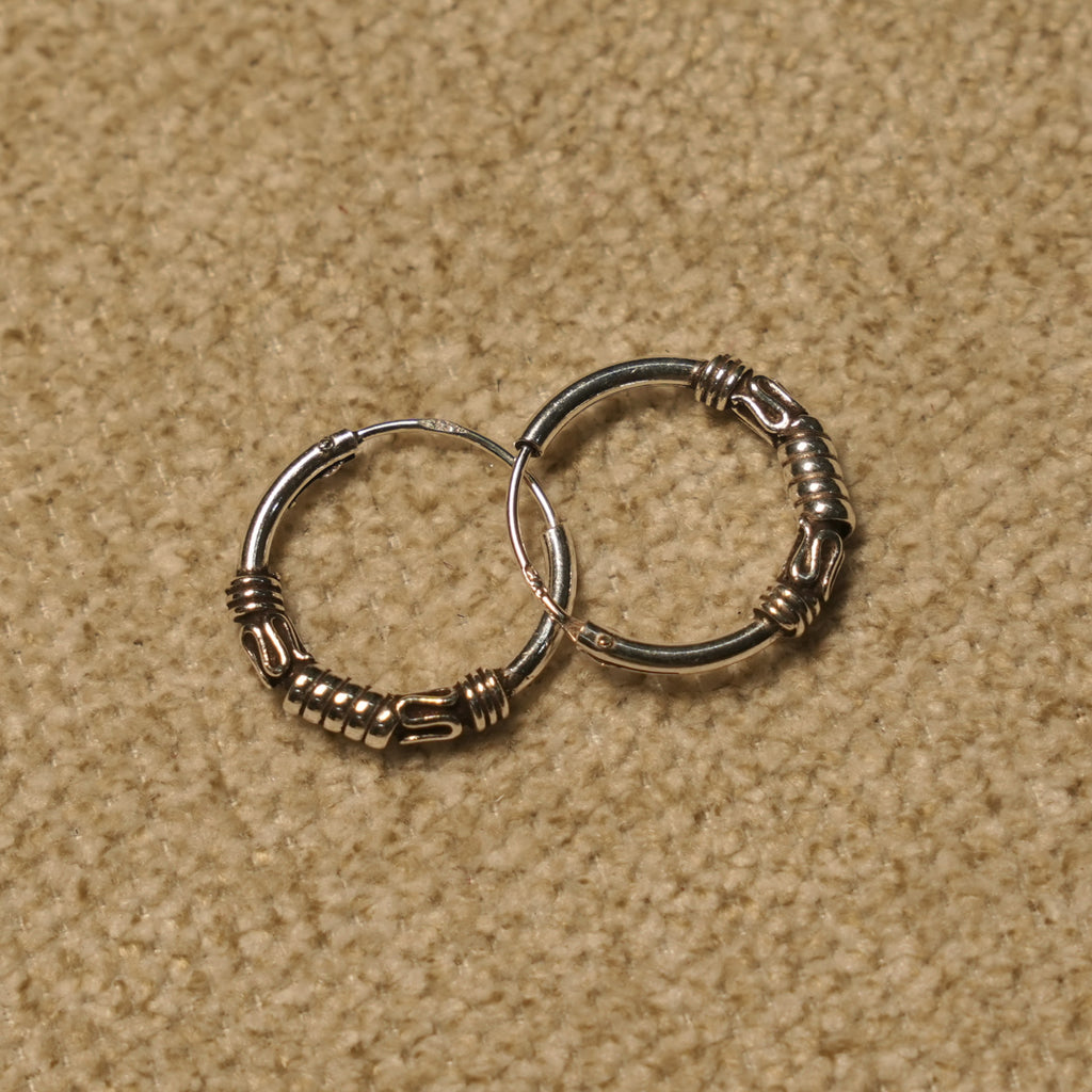 Angled view of the Bali hoop earrings showing the wrapped coil detailing along the lower curve of each hoop.