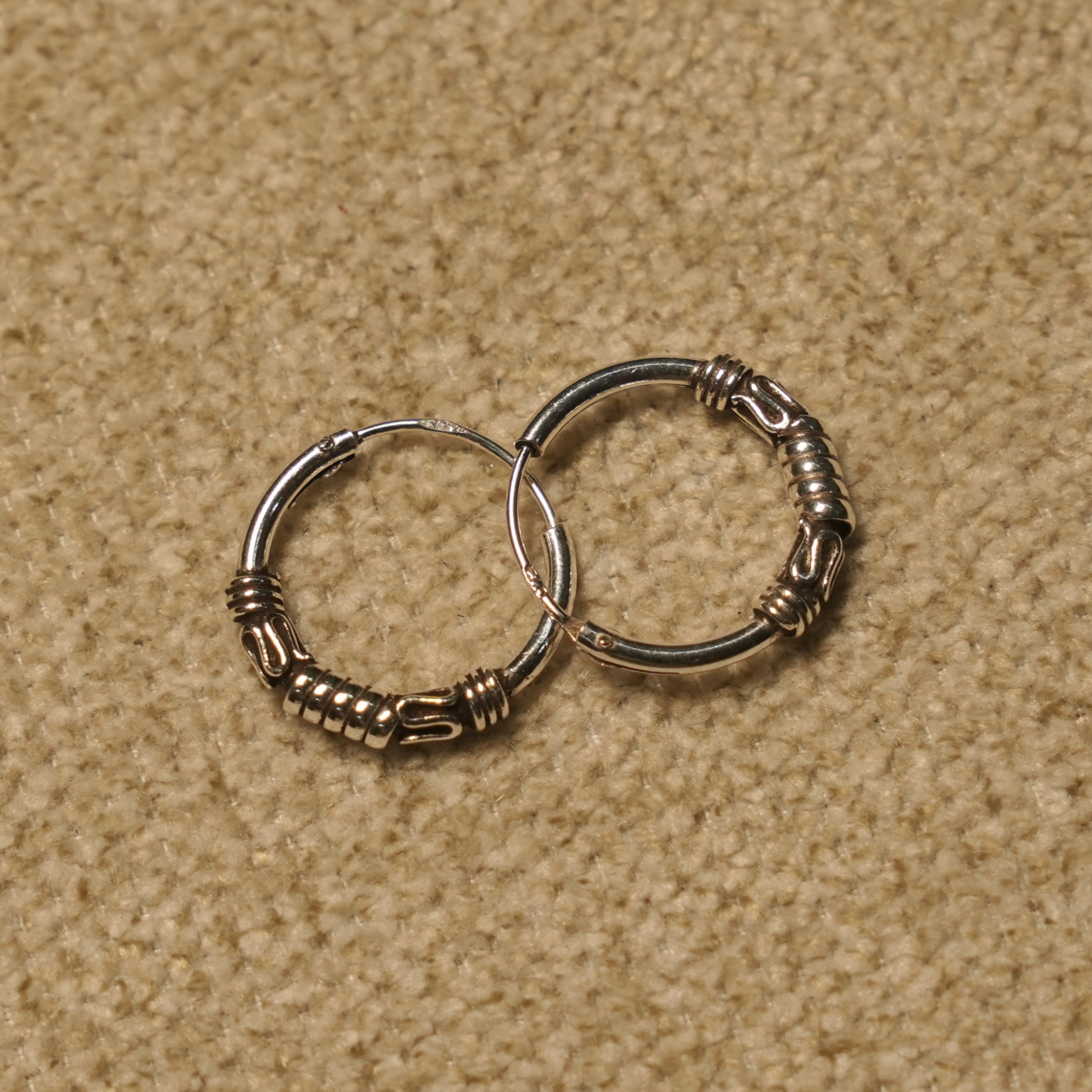 Angled view of the Bali hoop earrings showing the wrapped coil detailing along the lower curve of each hoop.