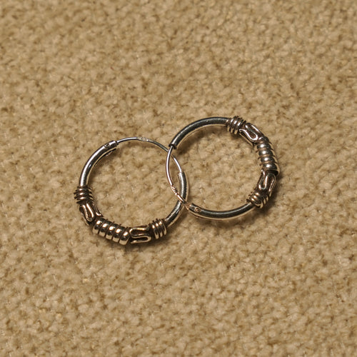 Angled view of the Bali hoop earrings showing the wrapped coil detailing along the lower curve of each hoop.
