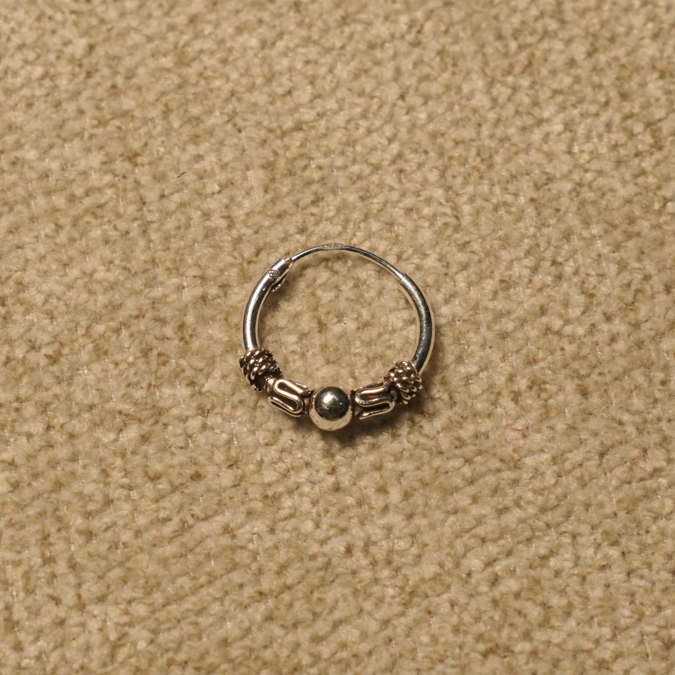 Single beaded Bali hoop in sterling silver showing the rope coil and scroll detailing around the centre bead.