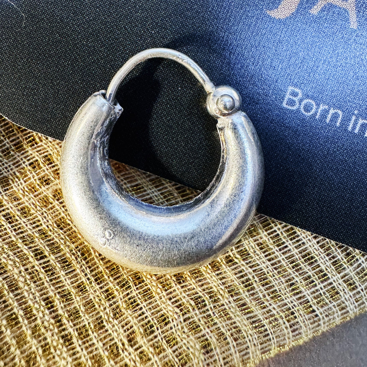 Large plain sterling silver kundal hoop earring, on cream fabric with the Javeri House card behind.