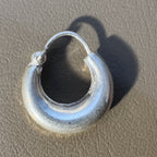 The large plain kundal hoop seen from the front on a tan surface.