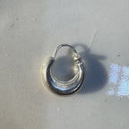 One small plain kundal hoop earring on a white dish, showing the hinged wire closure.