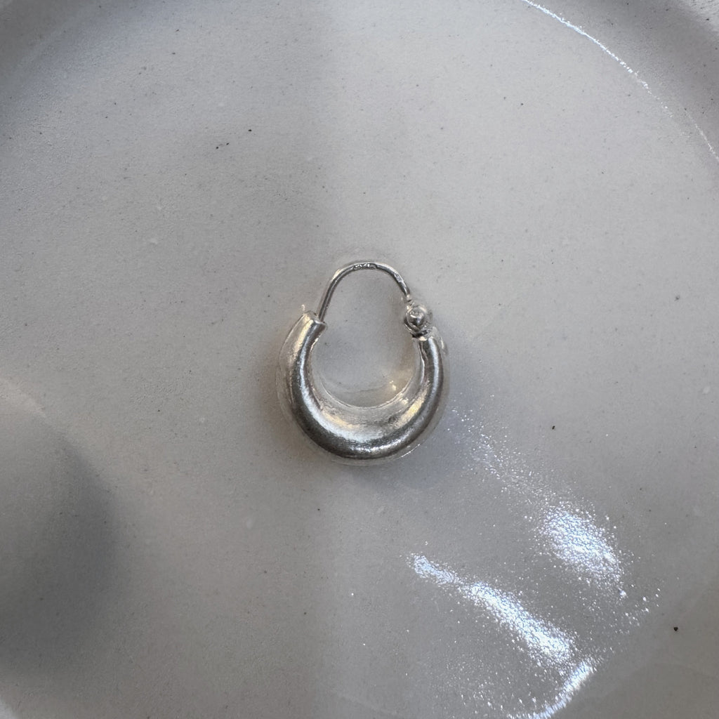 The small plain kundal hoop earring seen from a slight distance.