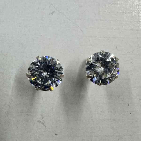 Pair of sterling silver stud earrings, each holding a round brilliant-cut cubic zirconia in a claw setting, on a pale grey surface.