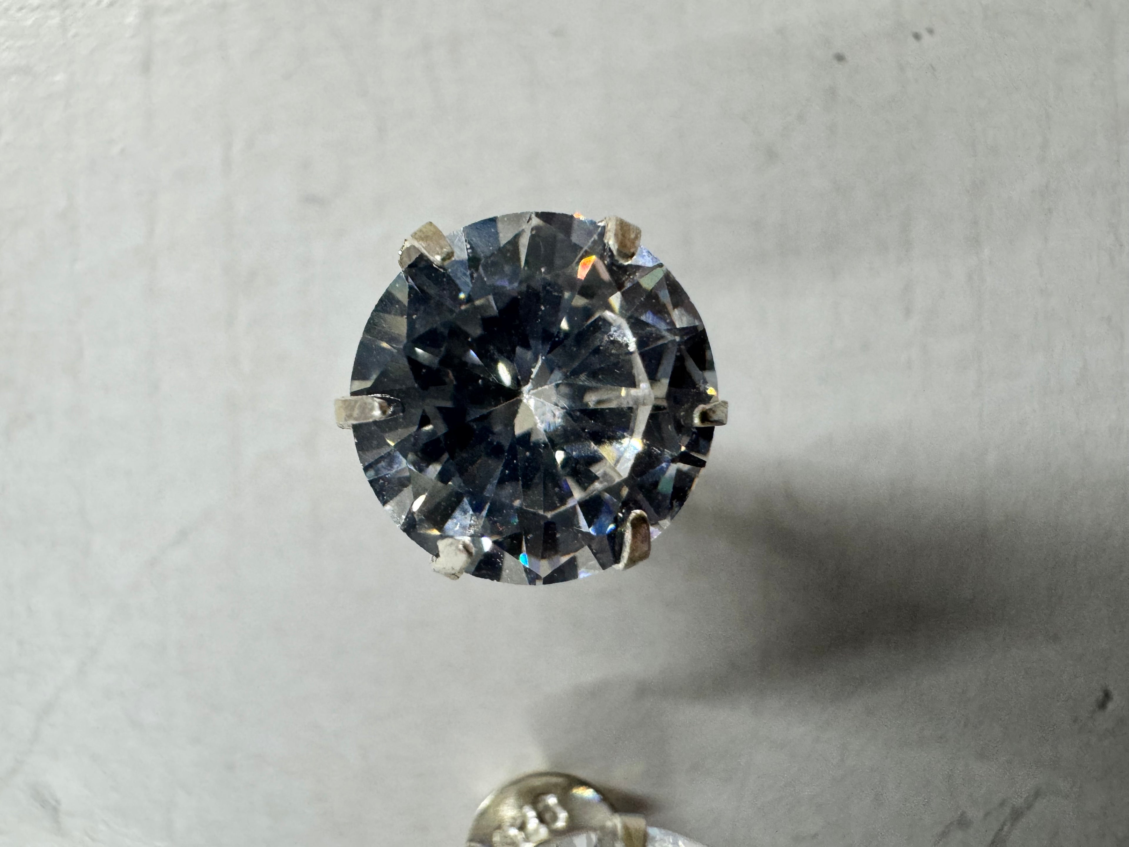 Close view of one sterling silver stud earring, showing the claws gripping the round cubic zirconia with the second stud behind.