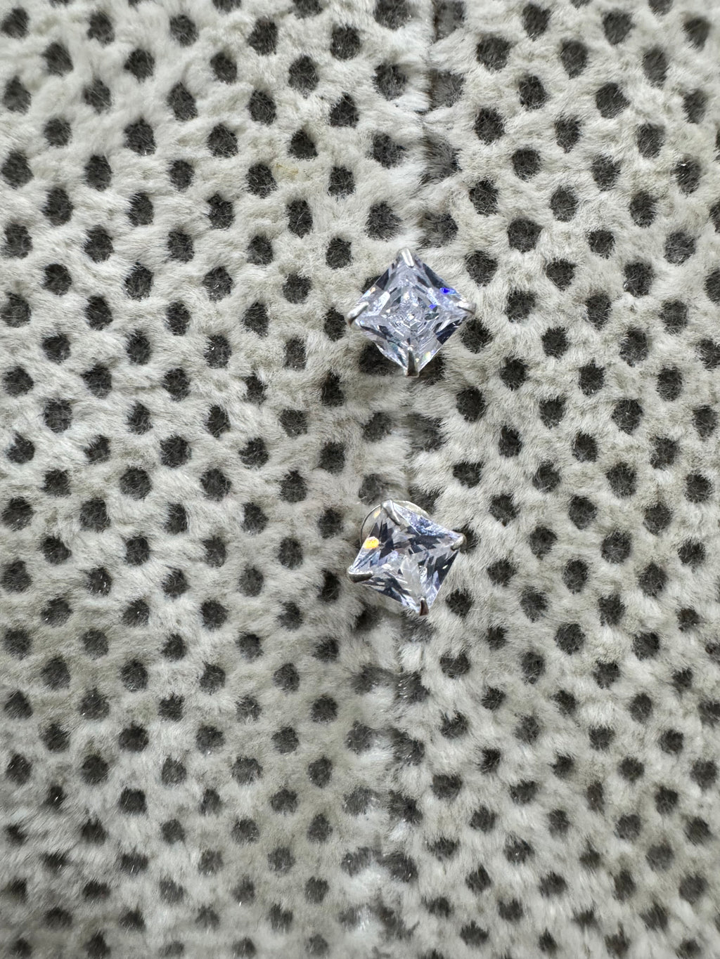 The two sterling silver studs set at an angle, showing the square cubic zirconia held at its corners by four claws.
