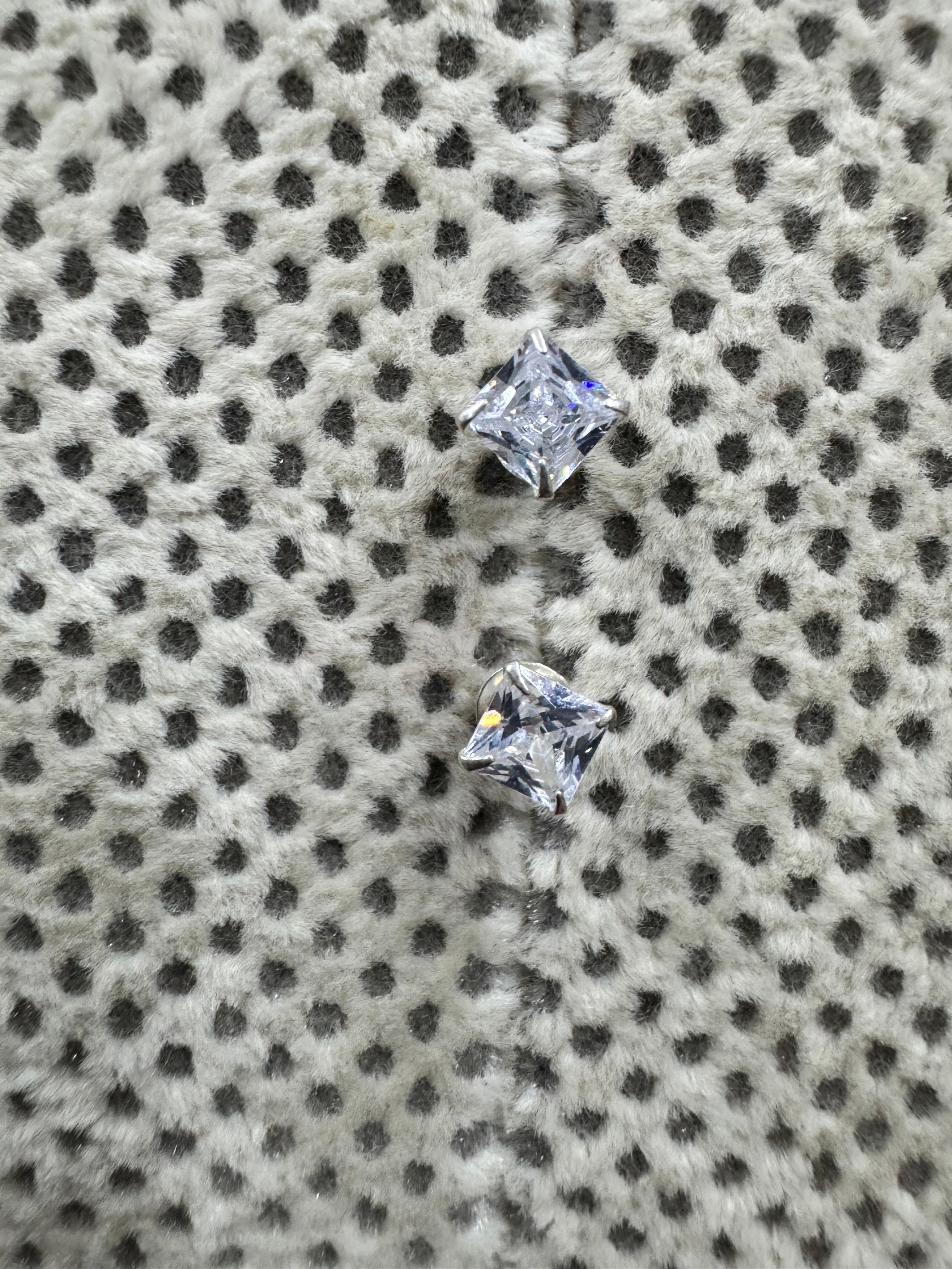 The two sterling silver studs set at an angle, showing the square cubic zirconia held at its corners by four claws.