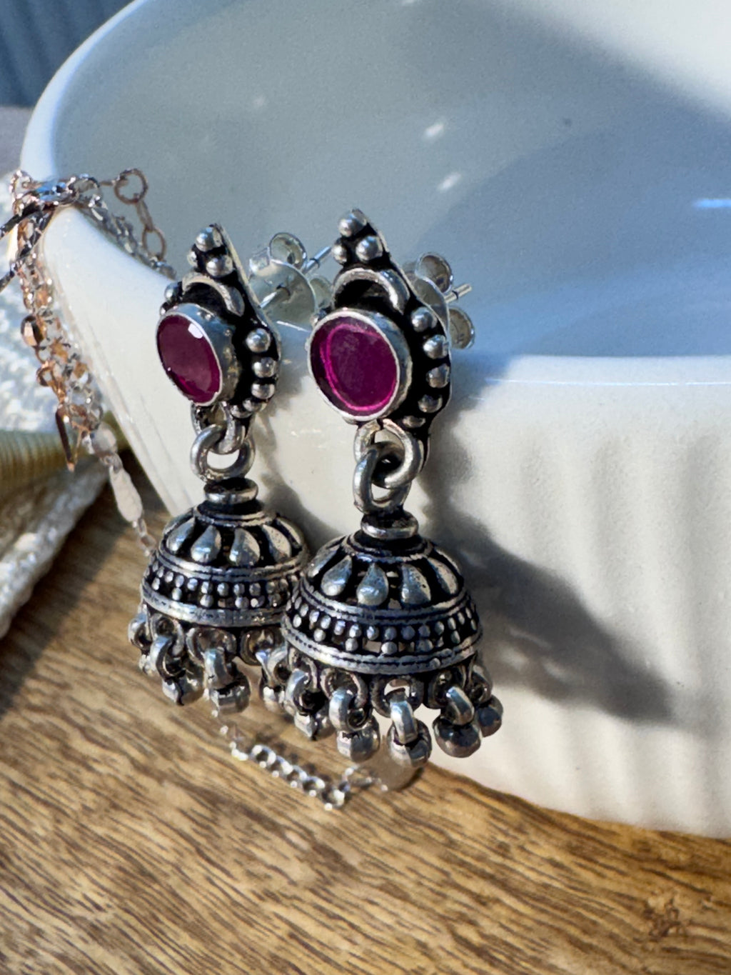 Close view of the oxidised jhumka dome with teardrop cutouts, below the deep pink glass stone top.