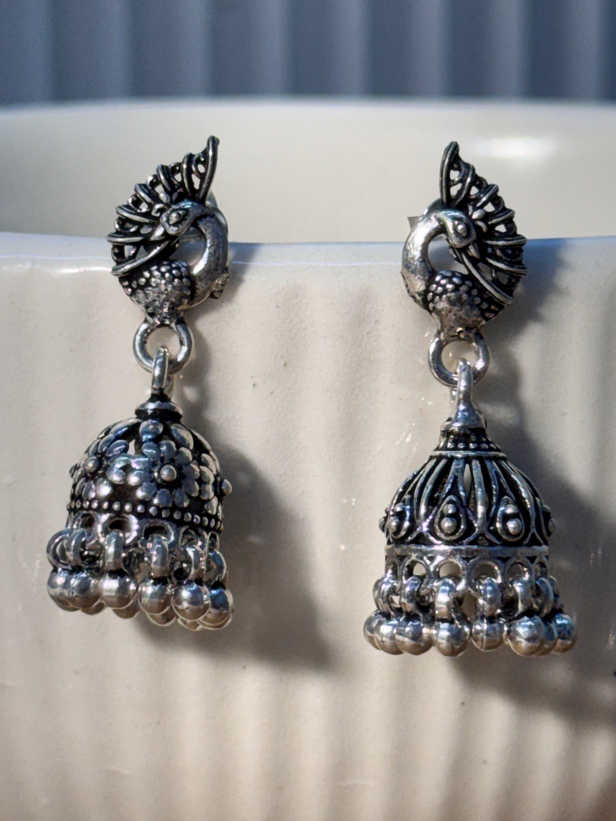 Oxidised sterling silver peacock stud jhumka with a teardrop cutout dome and bead fringe.
