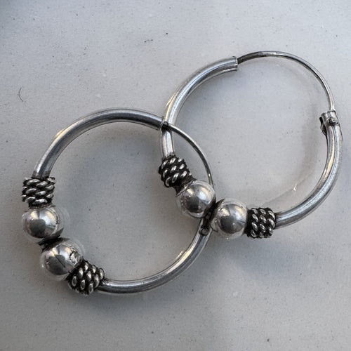 Pair of sterling silver Bali hoop earrings with two silver beads and oxidised twisted coils on each hoop.