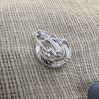 The pair of diamond-cut silver hoops on cream fabric.