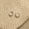 Pair of small sterling silver huggie hoops with ribbed texture, resting on a woven pouch with gold drawstring.