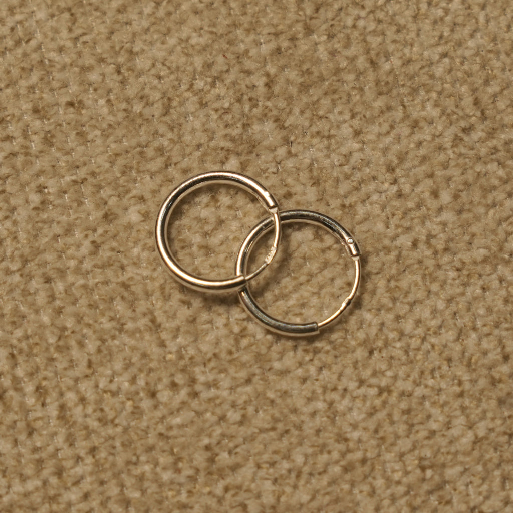 Close view of the slim sterling silver hoops showing the fine round-wire profile and hinged closure.