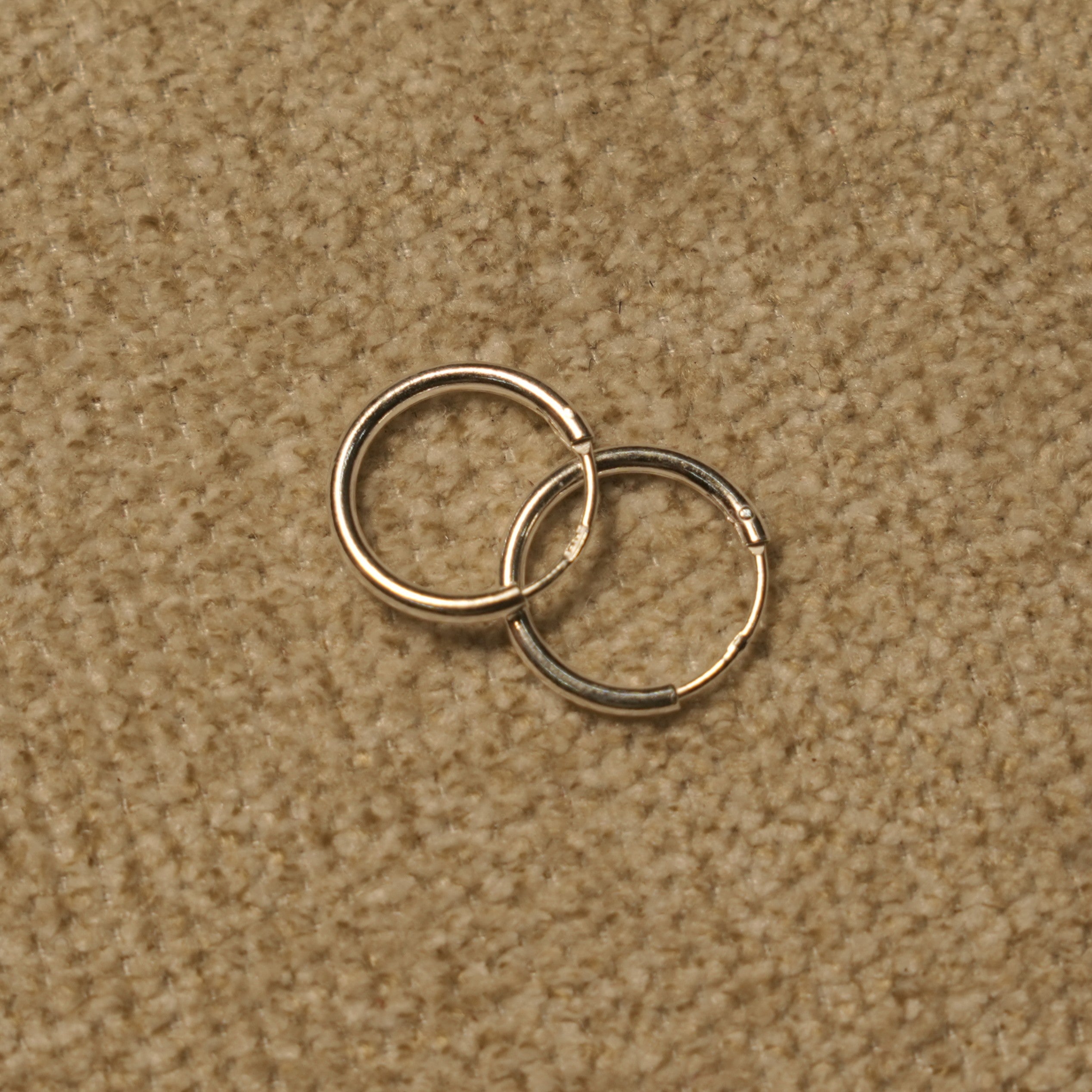 Close view of the slim sterling silver hoops showing the fine round-wire profile and hinged closure.