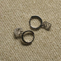 Pair of sterling silver hinged hoop earrings, each with a dangling heart charm textured with tiny cubic zirconia, on beige woven fabric.