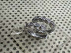 The sterling silver cubic zirconia huggie hoops on clear glass, with the 925 stamp visible inside the plain rear section.