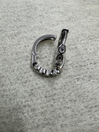 Single sterling silver huggie hoop earring opened at the hinge, showing the latch back and the teardrop bezels.