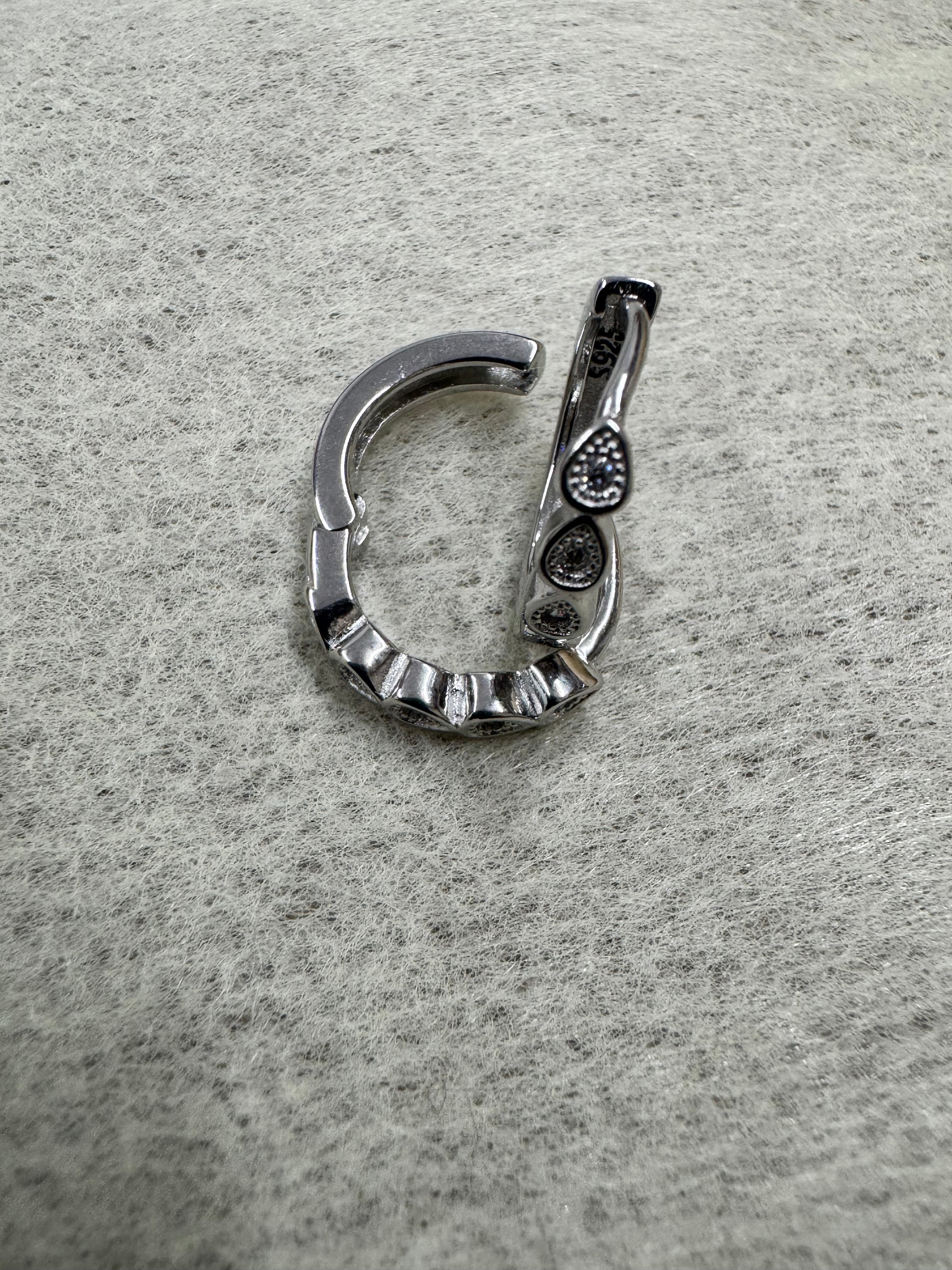 Single sterling silver huggie hoop earring opened at the hinge, showing the latch back and the teardrop bezels.