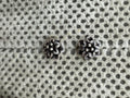Pair of oxidised sterling silver flower stud earrings on spotted grey fabric.