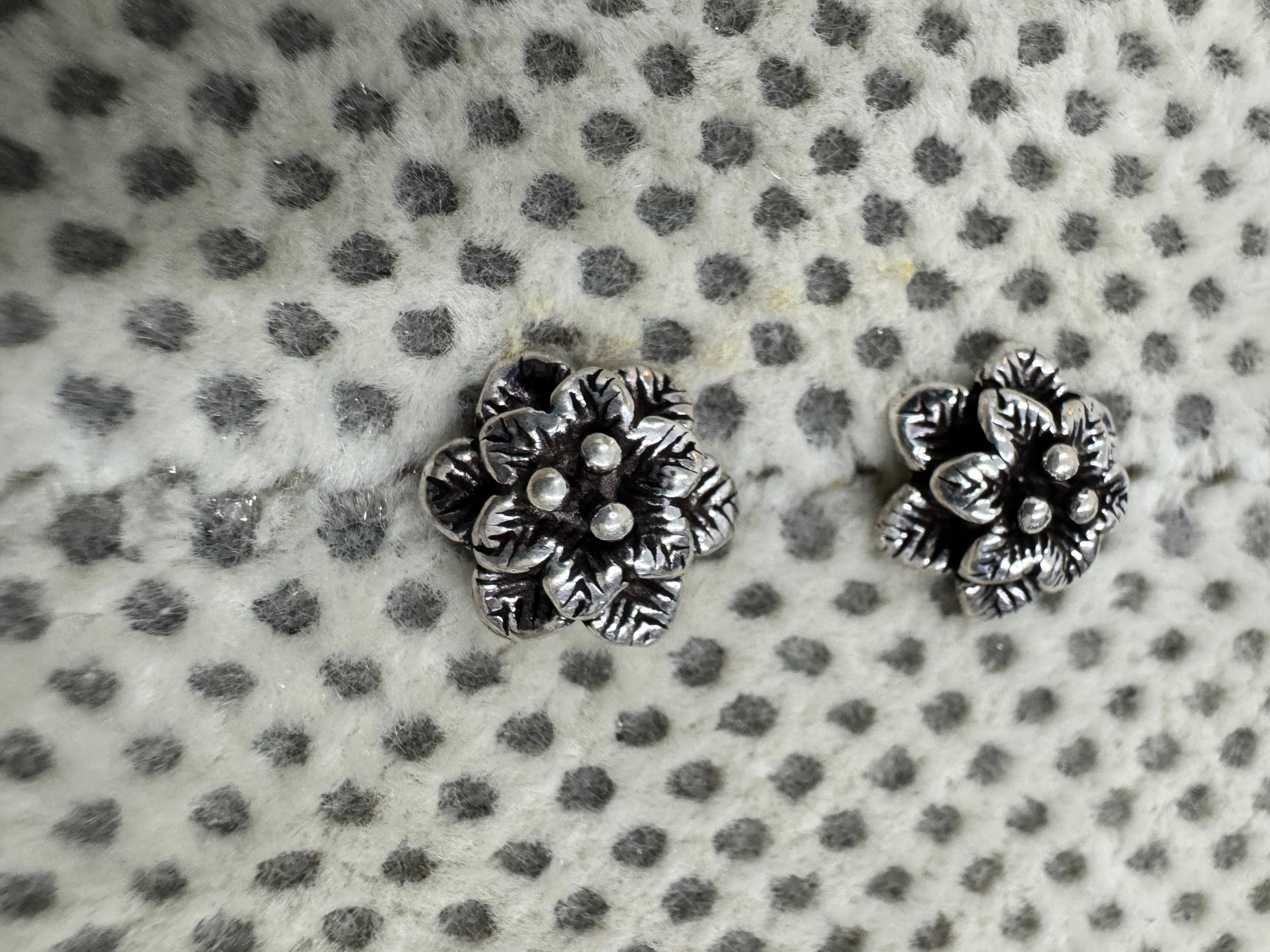 Close view of the layered petals and central granules on the oxidised sterling silver flower studs.
