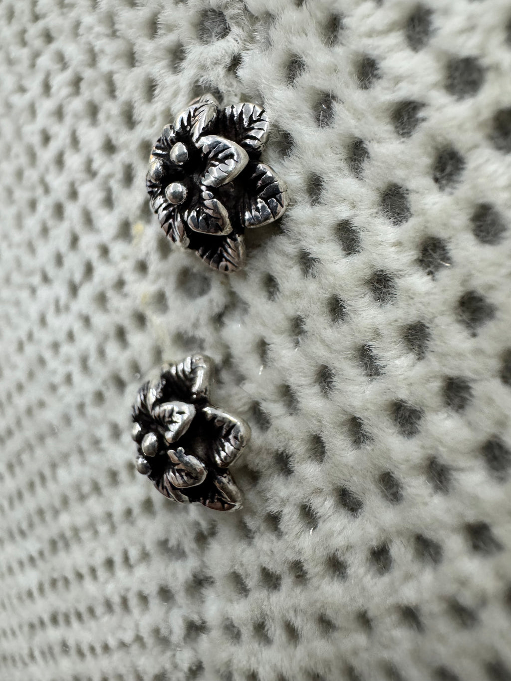 The sterling silver flower stud earrings seen at a low angle, showing the depth of the two petal tiers.