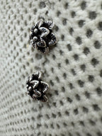 The sterling silver flower stud earrings seen at a low angle, showing the depth of the two petal tiers.