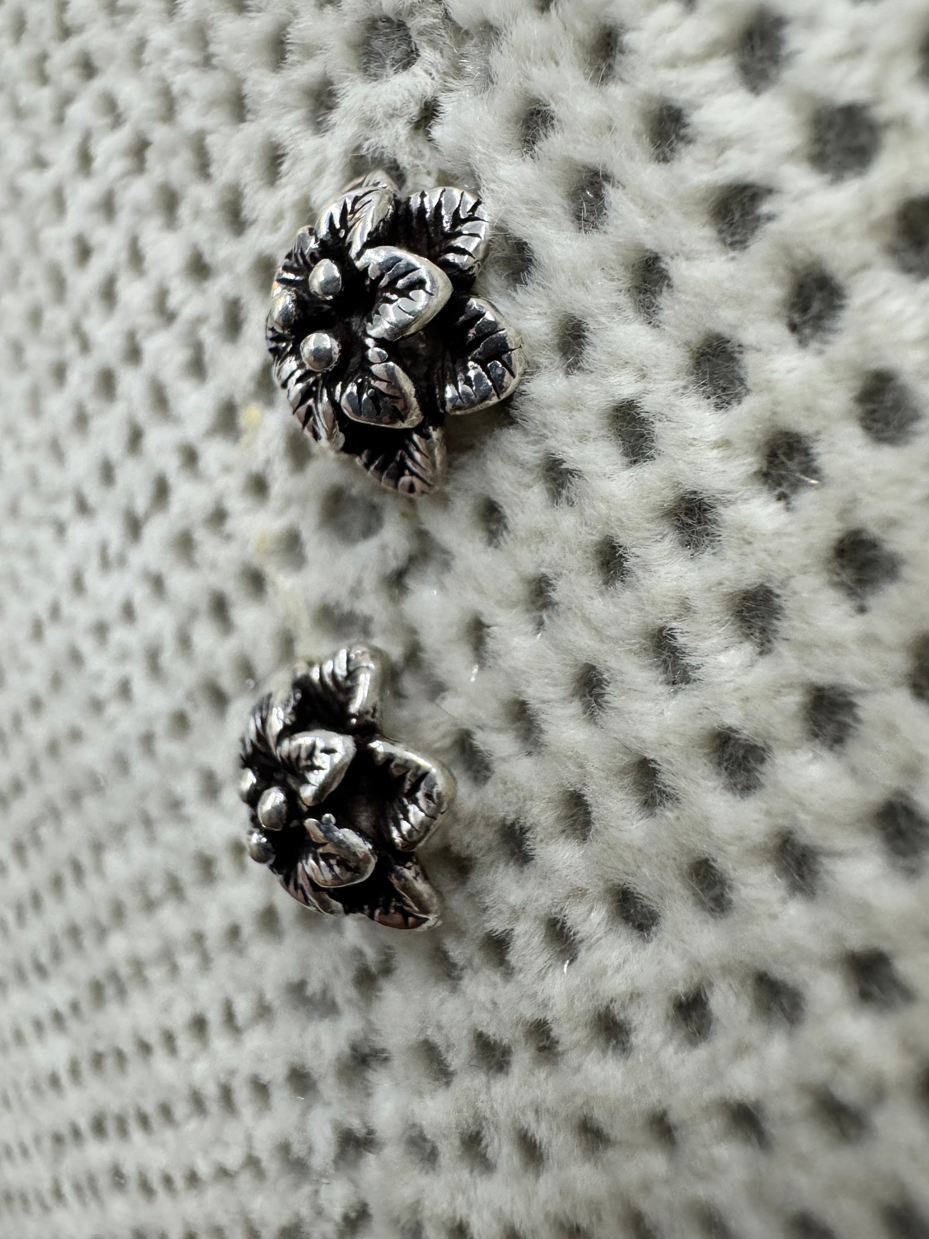The sterling silver flower stud earrings seen at a low angle, showing the depth of the two petal tiers.