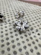 Side view of one oxidised sterling silver flower stud with its straight post and butterfly back.