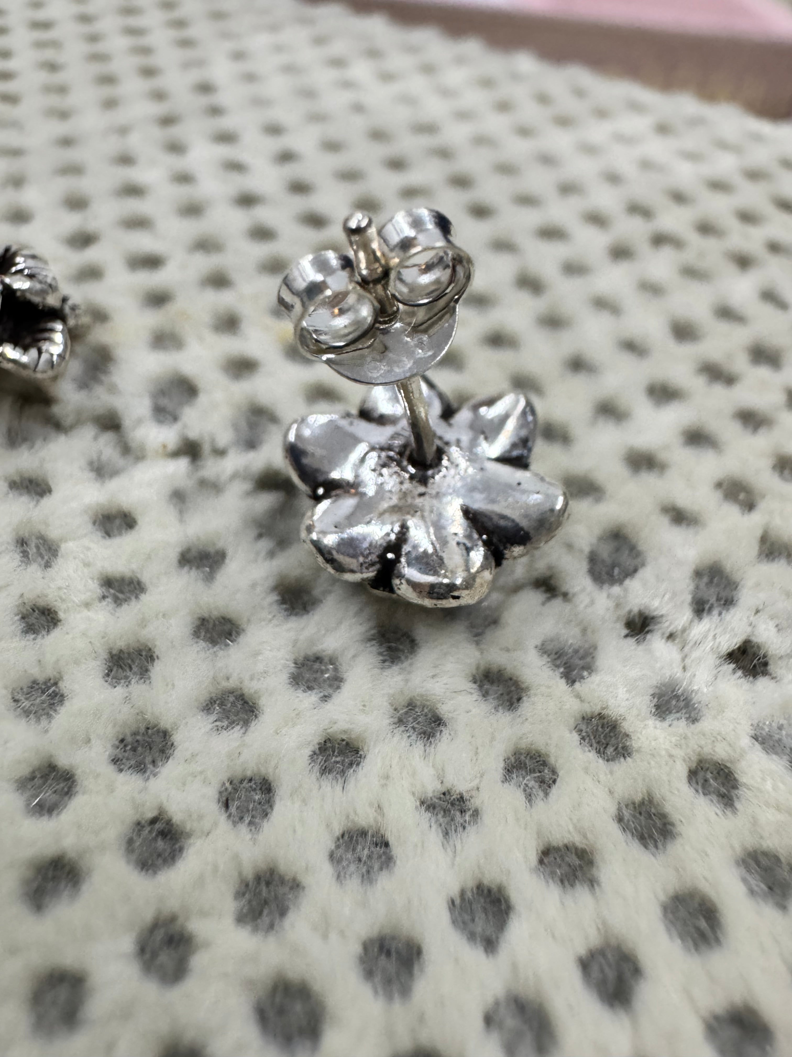 Side view of one oxidised sterling silver flower stud with its straight post and butterfly back.