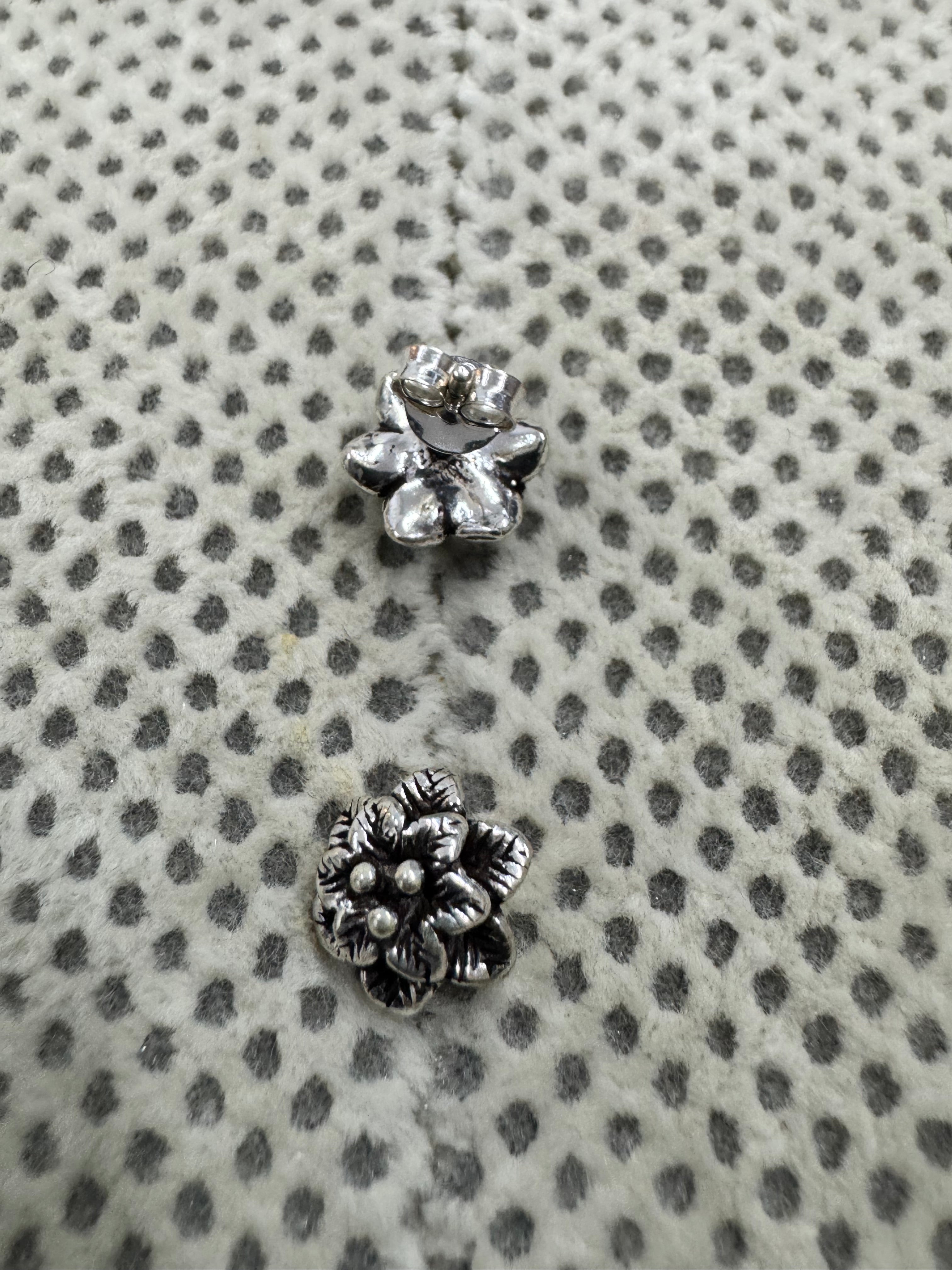 The pair of sterling silver flower studs, one turned to show the plain reverse and butterfly back.