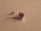 Angled view of the imitation ruby drop earrings, showing the bar studs and the swing of the square halos.