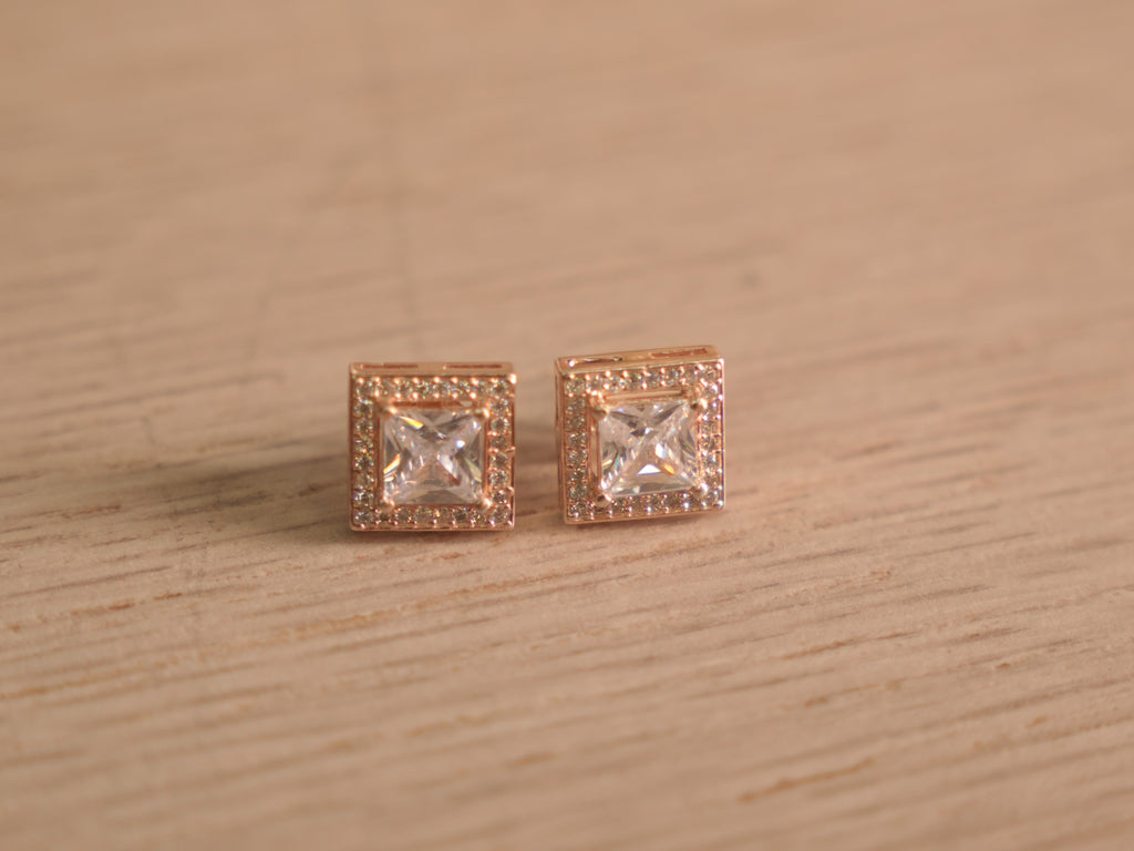 Pair of rose-tone stud earrings with square cut American Diamond centres inside square halos of smaller stones.