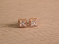 Pair of rose-tone stud earrings with square cut American Diamond centres inside square halos of smaller stones.