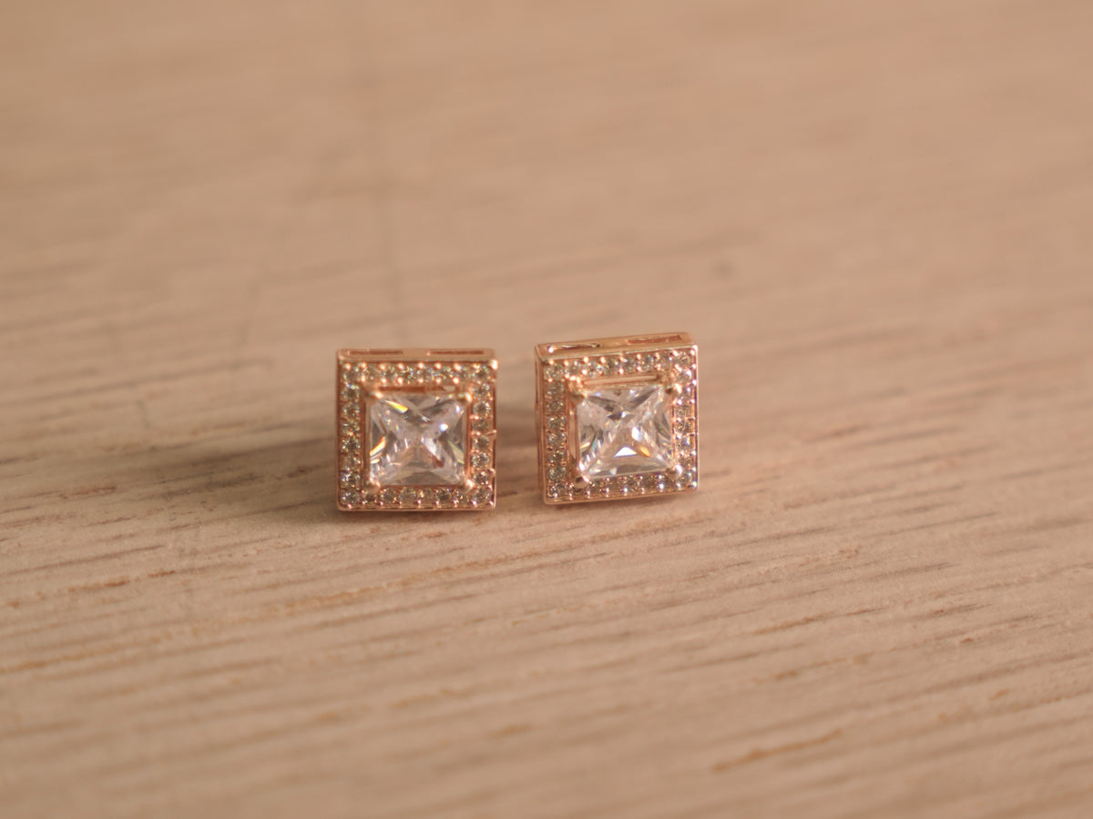 Pair of rose-tone stud earrings with square cut American Diamond centres inside square halos of smaller stones.