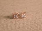 Angled view of the rose-tone square halo studs, showing the prong set centres and stepped halo edges.