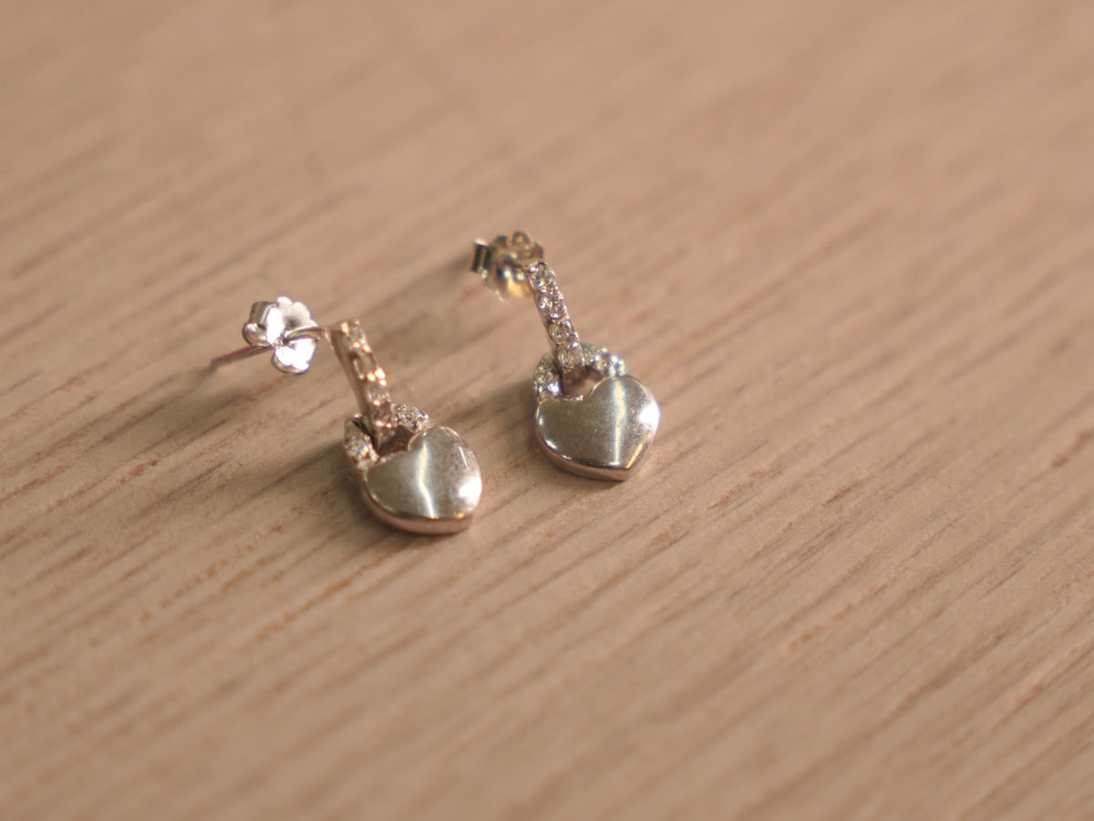 Close view of the heart padlock drops, showing the pave set bars and polished heart faces.