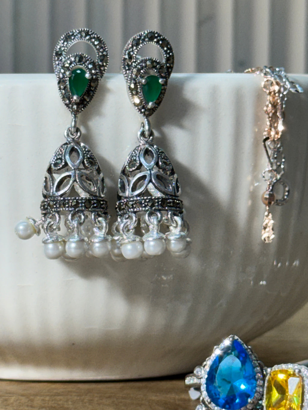 Pair of antique style sterling silver jhumkas with teardrop green glass stones and white bead fringes.