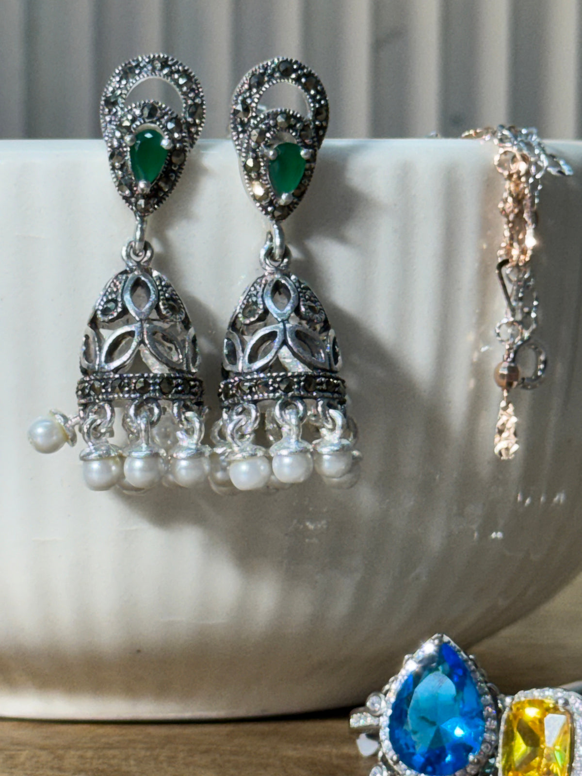 Pair of antique style sterling silver jhumkas with teardrop green glass stones and white bead fringes.