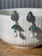 Pair of sterling silver peacock stud jhumkas with green glass stone cones and white drop beads.