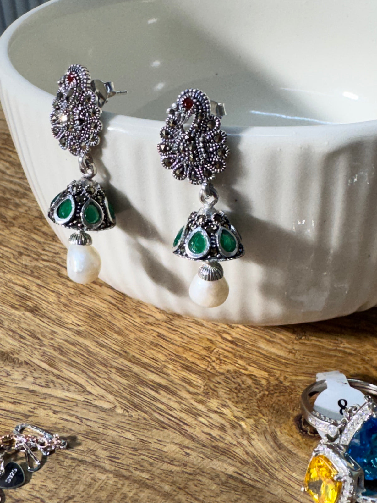 The peacock cone jhumkas resting on a plain background, showing the drop beads below the cones.